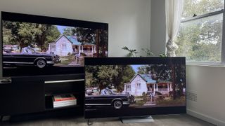 The LG G4 OLED TV on a TV stand, with the LG G3 OLED next to it on the floor, both showing the same scene from the opening of the movie A View to Kill