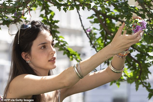 A Taylor Swift fan repairs her beaded bracelets at the Swiftie Tree on Cornelius Strasse