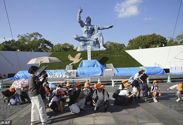 Visitors to the Peace Park crouch as an earthquake warning is issued in Nagasaki. Submarines in the Nankai Trough found that the chance of a major earthquake in the region was 'relatively higher than normal for the coming week'