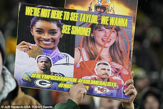 A Green Bay Packers fan holds up a sign with Taylor Swift and Simone Biles on it in 2023