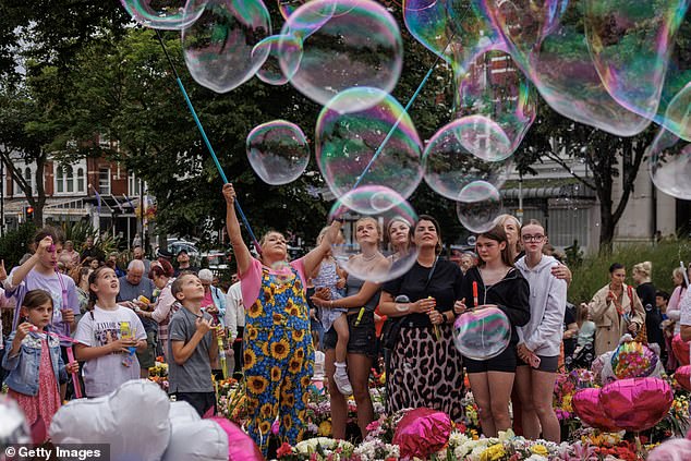 Community members, family and friends blow bubbles as people come together to mourn the victims of the horrific knife attack by holding a vigil at Atkinson on August 5