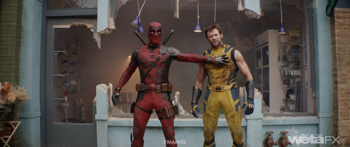 Deadpool (Ryan Reynolds) and Wolverine (Hugh Jackman) stand together in front of a burned-out storefront in Deadpool & Wolverine