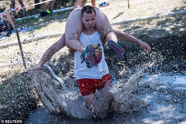 Competitors compete in a wife carrying championship in Tapiobicske, Hungary, August 10, 2024