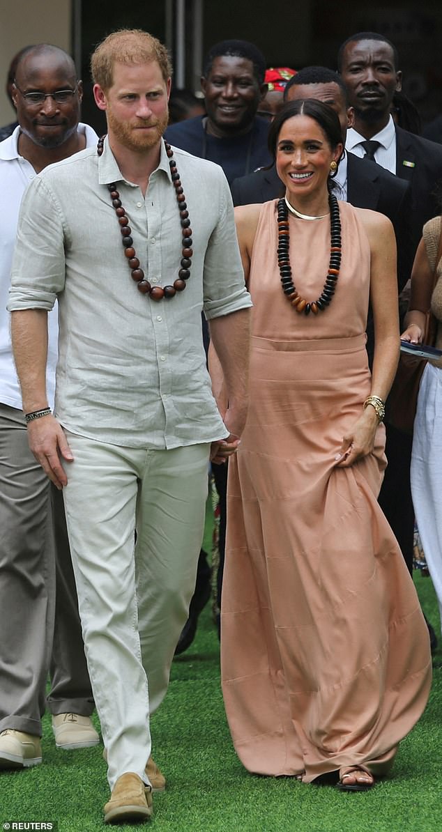 Prince Harry and Meghan walk away after meeting students at Lightway Academy in Abuja, Nigeria on May 10,