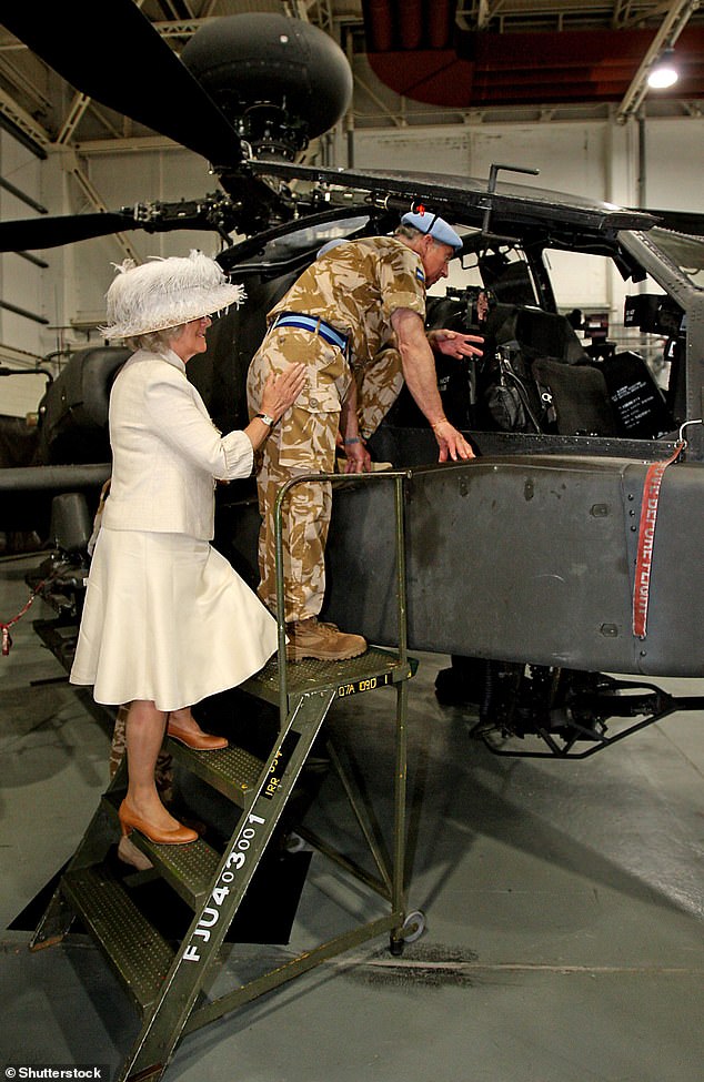 Camilla lends a helping hand to Charles as he climbs the steps to look at an Apache helicopter during a visit to Wattisham Airfield in Ipswich, 2009, where Charles presented service medals to members of the 4th Regiment Army Air Corps