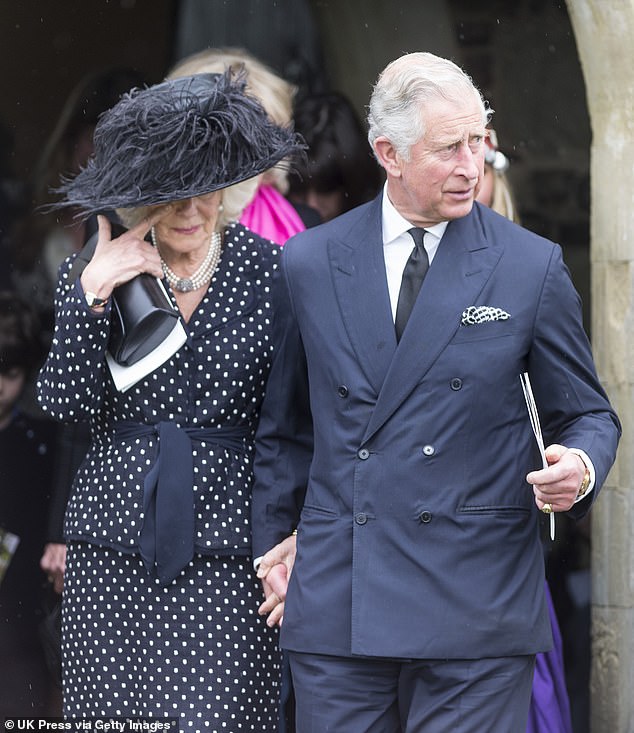 A tearful Camilla, in an elegant dark polka-dotted jacket and skirt, holds her husband's hand during the funeral of her brother Mark Shand at a church in Dorset, May 2014