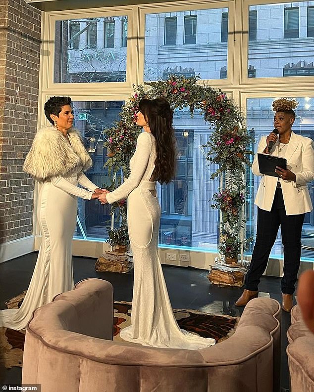 The two exchanged vows in front of a floral arch placed in front of a large window on what appeared to be an upper floor