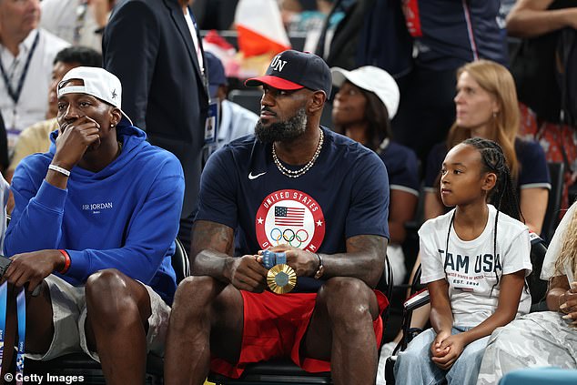 LeBron James looked on with his own gold medal after the men's championship victory on Saturday, sitting with daughter Zhuri Nova (right), 9, and teammate Bam Adebayo (left)