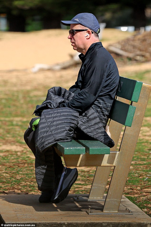 Mr Joyce, wearing a black Kathmandu puffer jacket, cotton sweatpants and a cap, appeared lost in thought as he sat on a beachside bench listening to his AirPods