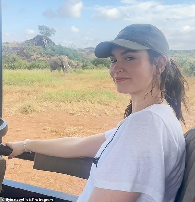 At one point she was sitting in a jeep watching some elephants nearby. She looked like a woman dressed in cream pants and a gray vest. Her brown hair was half hidden under a cap.