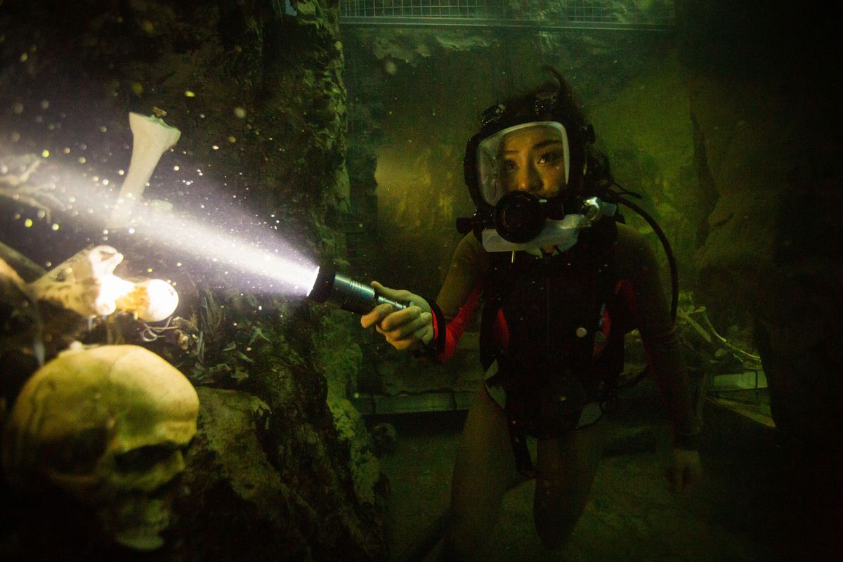 Brianne Tju holds a flashlight on a skull as she dives underwater in 47 Meters Down: Uncaged 