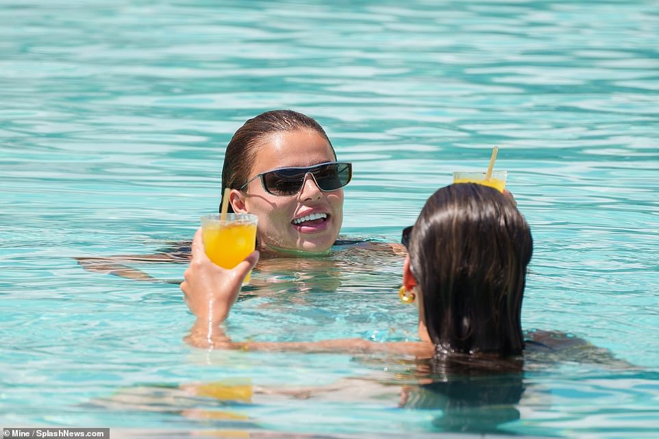 In this image, the sisters held on to orange drinks as they treaded water in the shallows