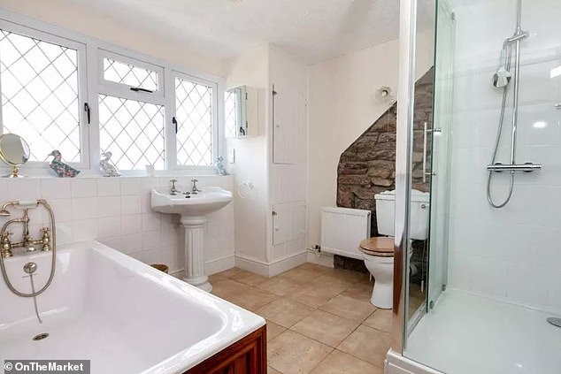 Photos from the property listing show the traditional stone wall of the cottage which is still visible in the main bathroom