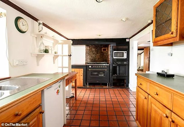 The kitchen currently features a gas hob and integrated oven and microwave, set amongst 70s style cabinetry