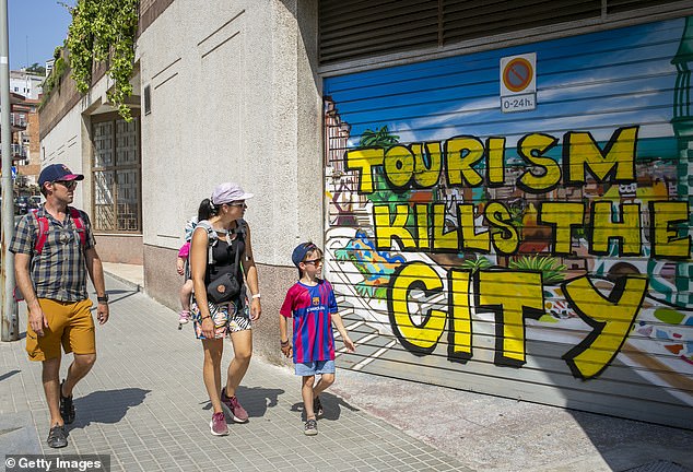 A family walk along anti-tourism graffiti in Barcelona