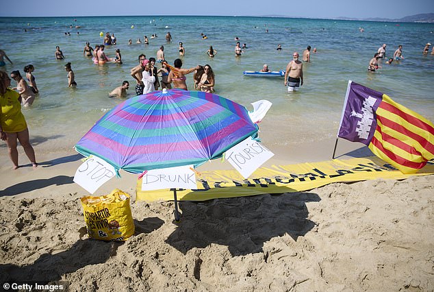 Three signs on a parasol on the beach with the text 'stop drunk tourists'