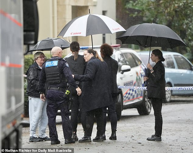 Detectives and police officers can be seen talking to the public at the crime scene in Carrara