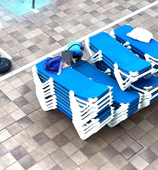 A man appears to be removing secured sunbeds in an attempt to get the best spot by the pool