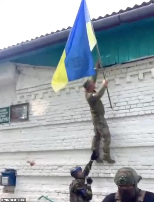 A Ukrainian soldier raises a Ukrainian flag in Guevo, Kursk Oblast, Russia, released on August 11, 2024 in this still image obtained from a social media video