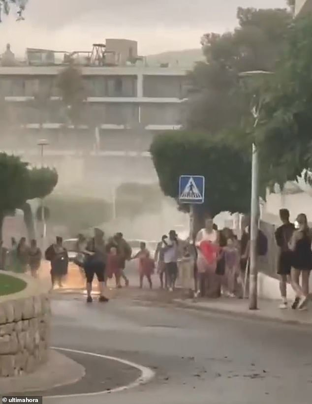 Holidaymakers flee a beach in Magaluf as storms hit the resort today