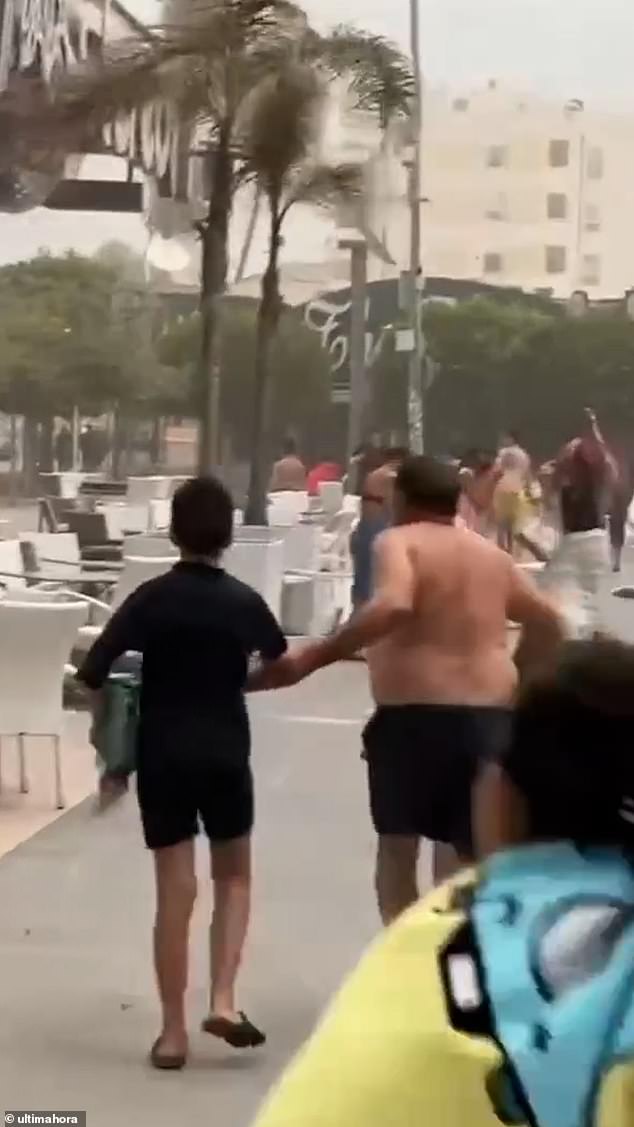 Tourists run away from the beach in Magaluf today as sudden storms hit