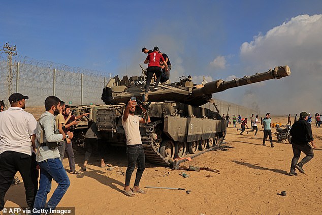 Alestinians take control of an Israeli Merkava battle tank after crossing the border fence with Israel from Khan Yunis in the southern Gaza Strip on October 7, 2023