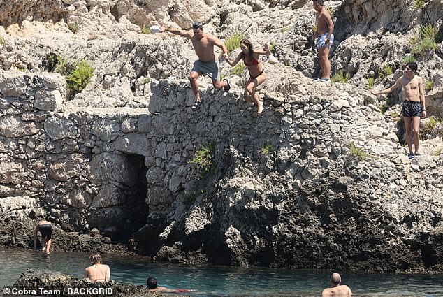 The couple jumped off a cliff into the ocean along with beachgoers as others watched.