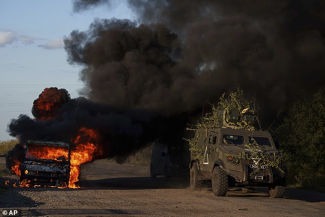 A Ukrainian armored vehicle drives past a burned car near the border on Wednesday