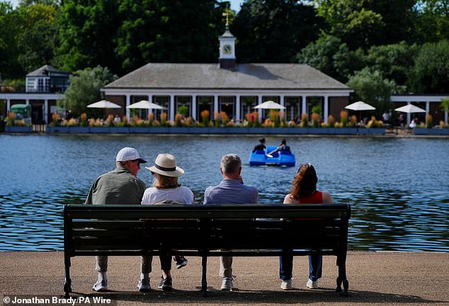 A group of people observe pedal boaters at the Serpentine in London's Hyde Park on Tuesday