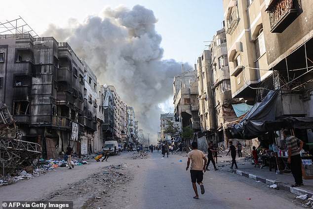 Palestinians run toward a column of smoke rising after the Israeli bombardment of a school complex on August 3