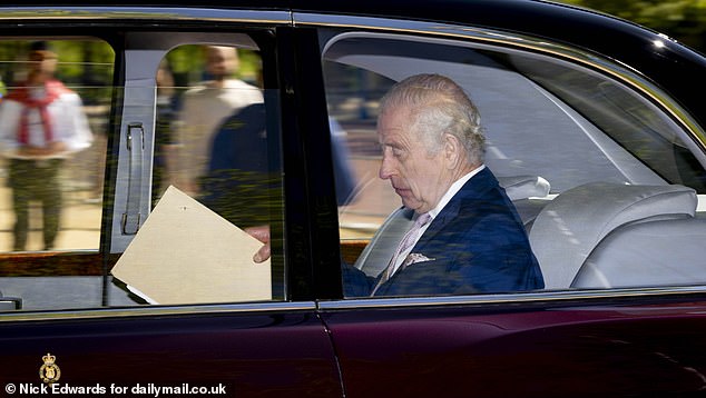 King Charles III is pictured with papers in his hands as he arrives at Clarence House in London, as Harry is about to leave