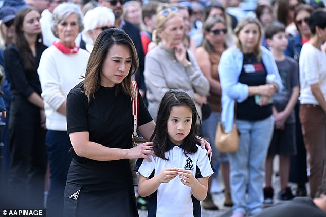 A young girl and her mother are seen at the vigil in Emerald Lakes on Friday