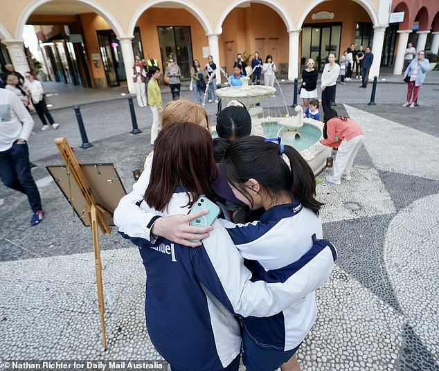 A group of students from Emmanuel College are seen hugging each other during the vigil