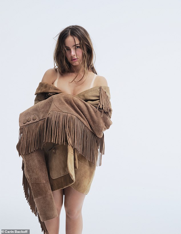 In this image she appeared to be naked as she wore a beige suede fringed jacket wrapped around her chest