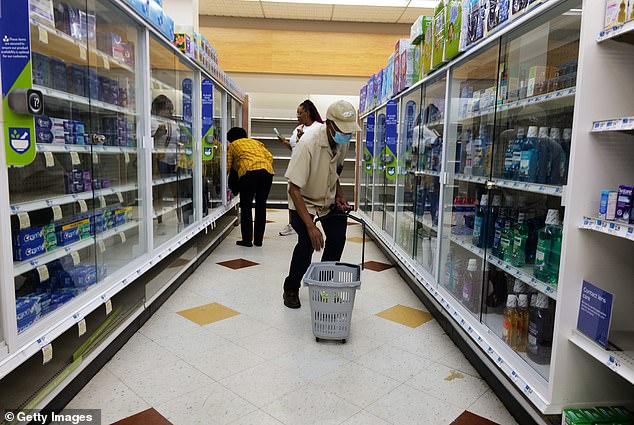 Three people browse the sparse shelves of a Brooklyn Rite Aid in August 2023, months before the company reportedly went bankrupt