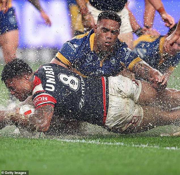 Roosters' Spencer Leniu scores a try by sliding through a huge puddle of water at Allianz Stadium on Friday