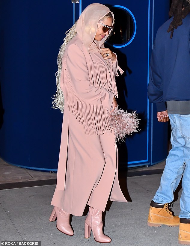 She continued to embrace her inner cowgirl in a pastel pink tasselled coat and added a semi-sheer scarf wrapped around her head