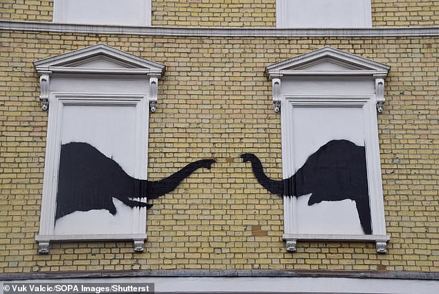 The artwork, which was pictured before it was damaged, shows two elephants poking their heads out of white windows