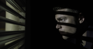 Peter Sutherland hides in a closet in The Night Agent season 1