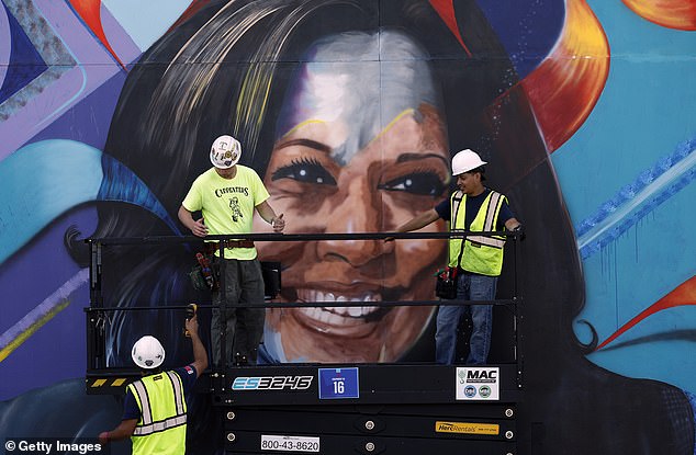 Workers construct a mural of Democratic presidential candidate and Vice President Kamala Harris outside the United Center on August 16, 2024 in Chicago, Illinois