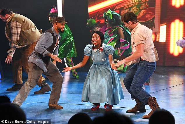 In the photos, the singer, dressed in a brown baker's boy, gray shirt and brown vest, smiled as he sang and danced alongside production manager Dorothy