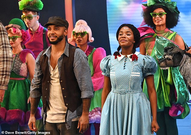 Aston grinned at the audience as he and the rest of the cast opened their curtain as the audience applauded