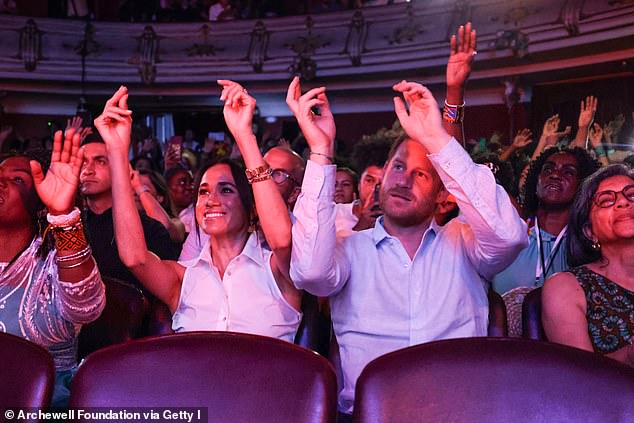 Meghan and Harry raise their hands as they attend Afro Women and Power event