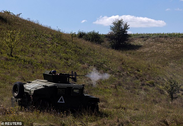 A Ukrainian soldier fires a Browning machine gun mounted on a Humvee military vehicle during a training exercise in the Sumy region, near the Russian border