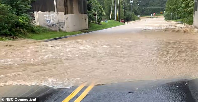 Pictured: Floodwaters gush over a road in Monroe, Connecticut on Monday