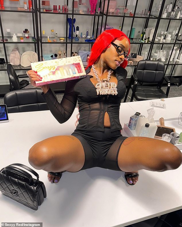 The U My Everything rapper wore her signature red wig with businesswoman-style glasses and wore her massive 'ghetto princess' diamond medallion necklace