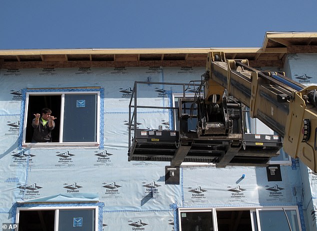 The average sales price of a home in the Flickertail State was $201,991 last year, up from $168,105 in 2011. (Pictured: Construction workers lift materials into a new apartment complex in Bismarck in 2012)