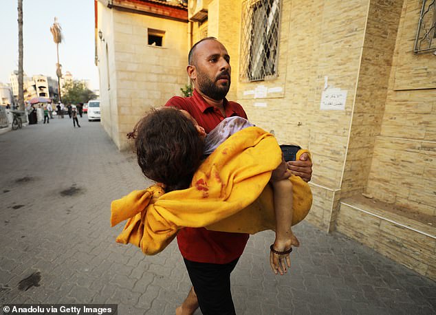 The 10-month conflict has reportedly left more than 40,000 people dead, including thousands of women and children (pictured: A man carries the lifeless body of a Palestinian girl to Al-Ahli Arab hospital after an Israeli shelling of a group of civilians)