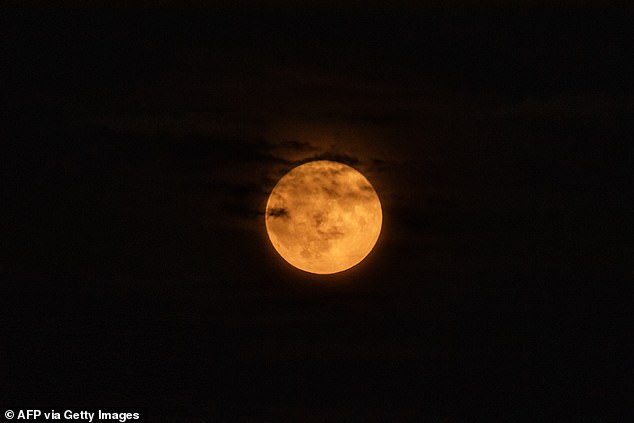 Last night's moon also appeared red or orange to many in the Northern Hemisphere due to the buildup of wildfire smoke in the atmosphere. Pictured is the supermoon over Boston, Massachusetts