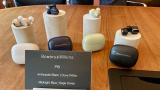 Bowers & Wilkins Pi8 earbuds held in a hand on a grassy background